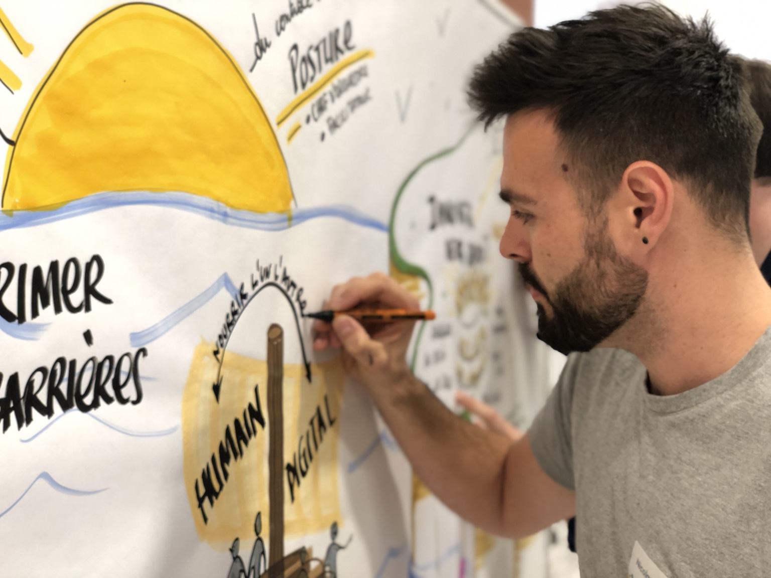 Nicolas Verdot, feutre en main, dessine une fresque en direct pendant un atelier.